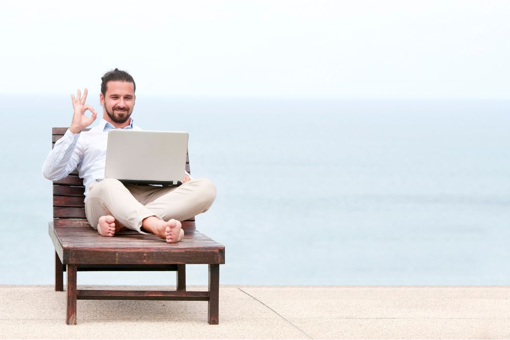 A Shopify SEO expert freelancer working on his laptop at the beach